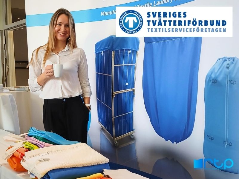 Przedstawicielka firmy RTP Radom prezentuje ofertę tekstyliów przemysłowych, w tym worki i wózki transportowe, na tle logo Sveriges Tvätteriförbund.